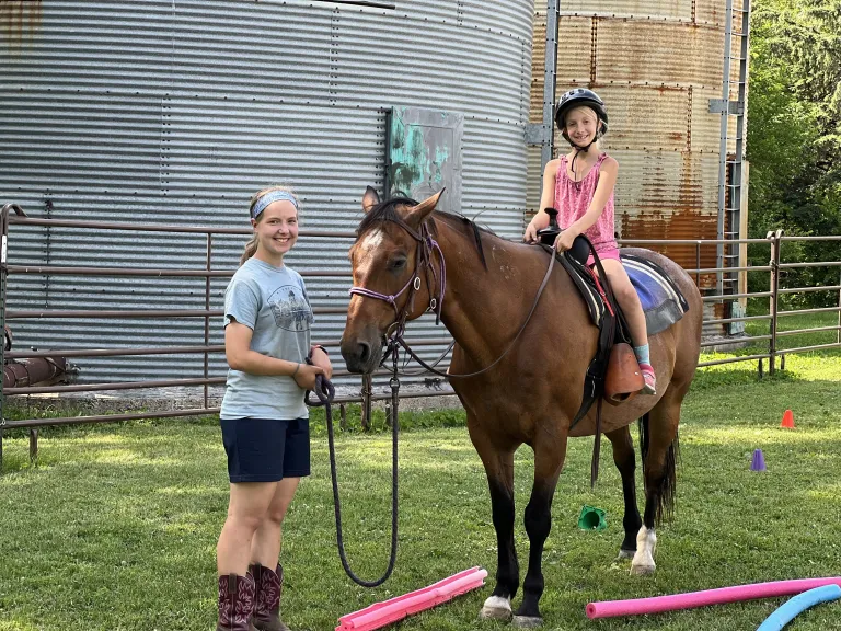 Girl help a young girl on horse