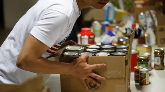 InFaith volunteer picking up box of canned goods