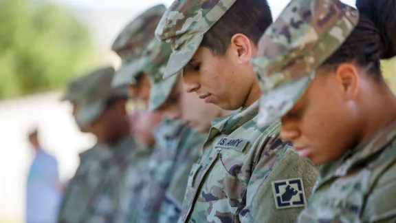 service men and women bowing heads in prayer