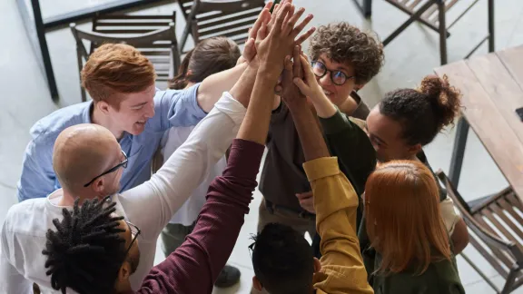 cross-cultural team with hands grouped together in the air