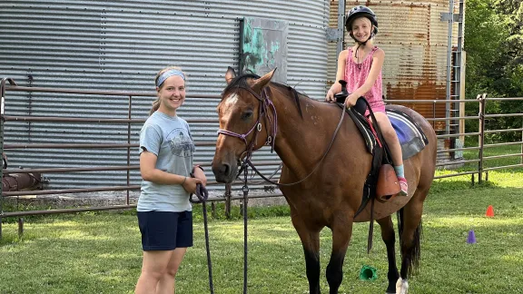 Girl help a young girl on horse