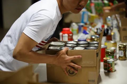 InFaith volunteer picking up box of canned goods