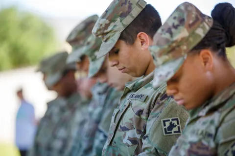 service men and women bowing heads in prayer