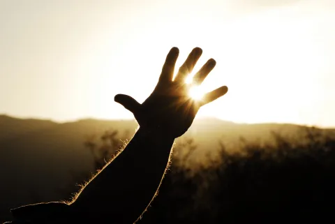rural ministry leader raising hand towards setting sun